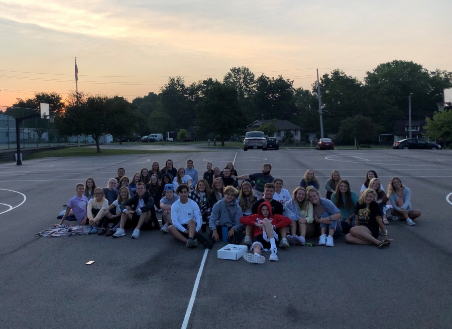 people sitting in parking lot with sunrise behind them